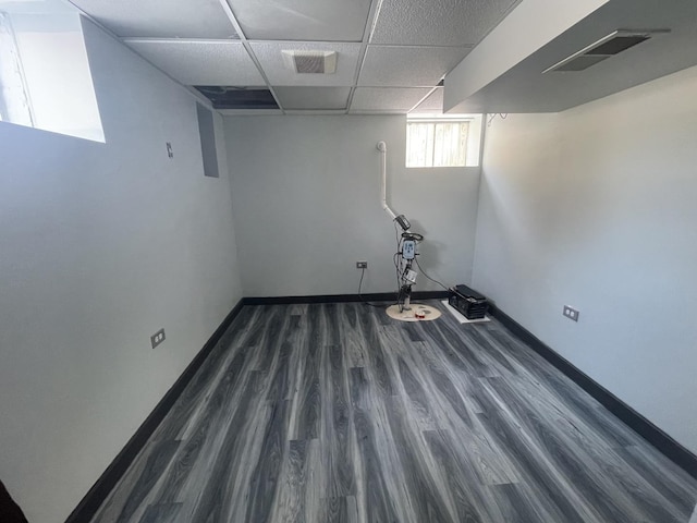 below grade area featuring a drop ceiling, wood finished floors, and baseboards