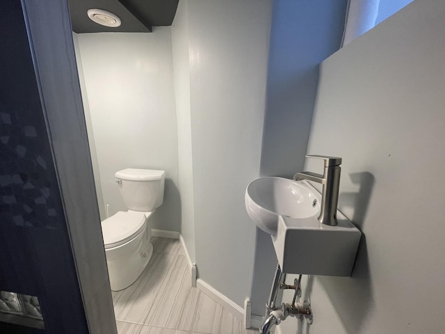 half bath featuring toilet and baseboards