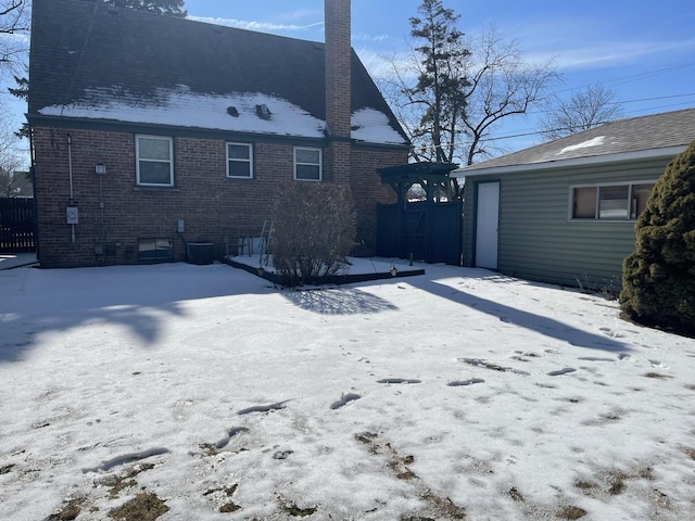 snow covered house with brick siding and a chimney