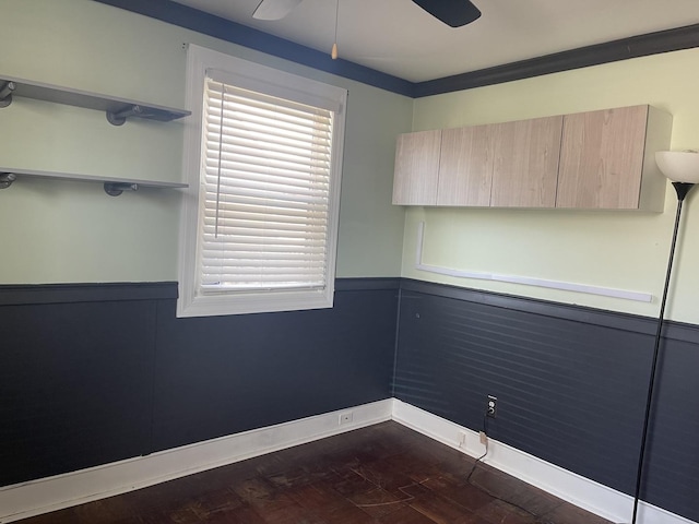 unfurnished room with dark wood-style floors, baseboards, a ceiling fan, and wainscoting