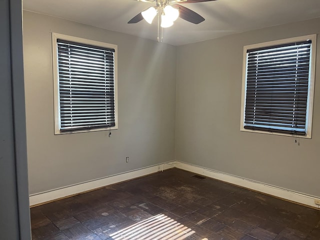 unfurnished room featuring a ceiling fan and baseboards