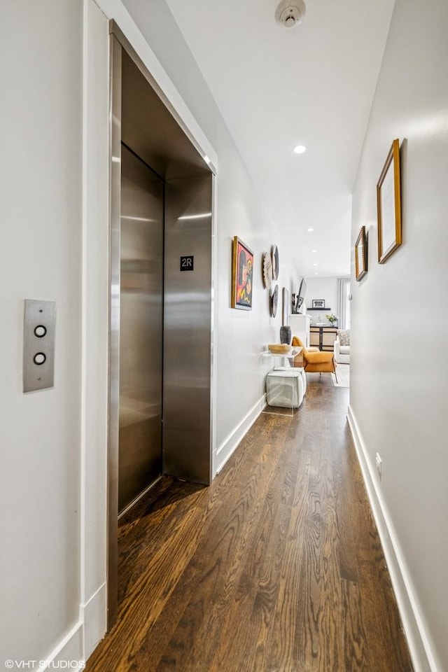 hallway featuring dark wood-type flooring, elevator, recessed lighting, and baseboards