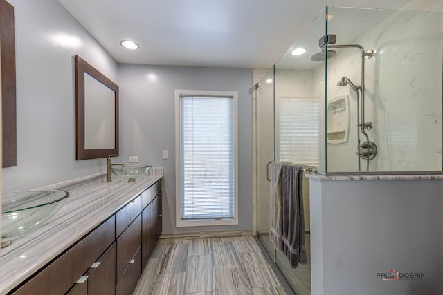 bathroom featuring double vanity, a shower stall, a sink, and recessed lighting