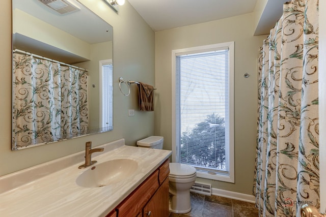 bathroom with toilet, vanity, visible vents, and baseboards