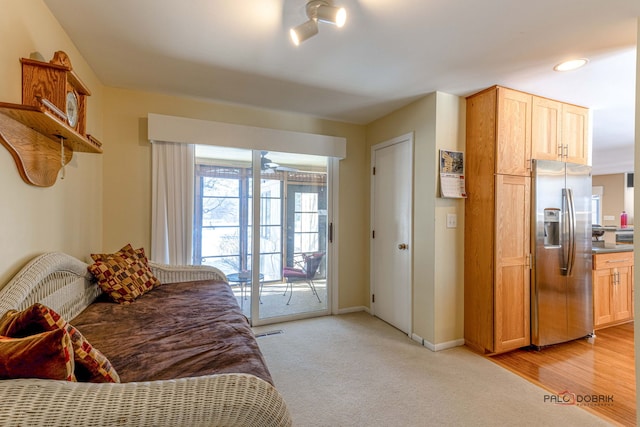 bedroom featuring baseboards, stainless steel refrigerator with ice dispenser, light colored carpet, and access to exterior