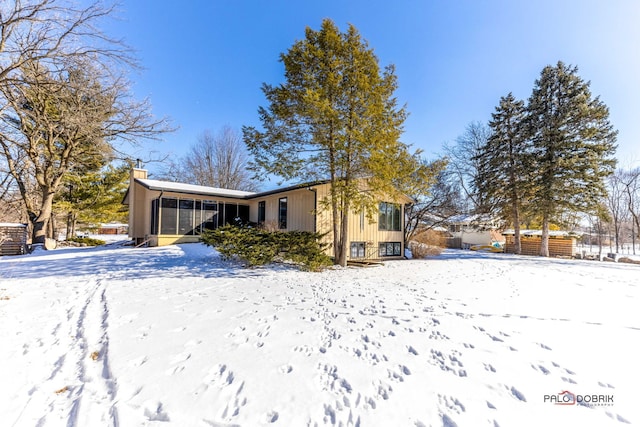 snow covered property featuring a chimney and a sunroom