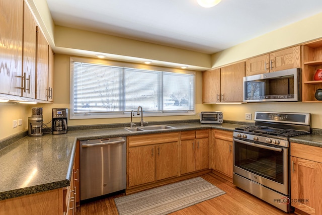 kitchen with stainless steel appliances, a sink, open shelves, brown cabinetry, and dark countertops