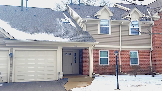 view of front facade with an attached garage, a shingled roof, aphalt driveway, and brick siding