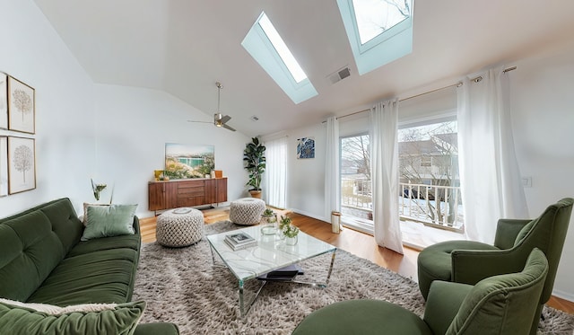 living area featuring ceiling fan, high vaulted ceiling, a skylight, wood finished floors, and visible vents