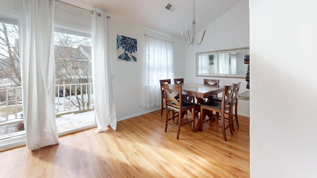 dining room with baseboards, visible vents, wood finished floors, an inviting chandelier, and vaulted ceiling