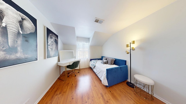 bedroom with baseboards, visible vents, and wood finished floors