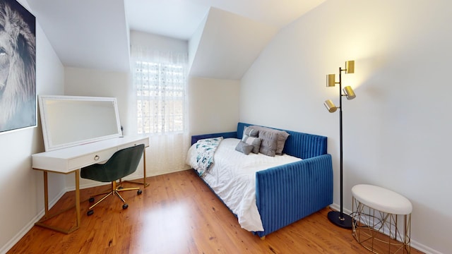 bedroom with lofted ceiling and wood finished floors