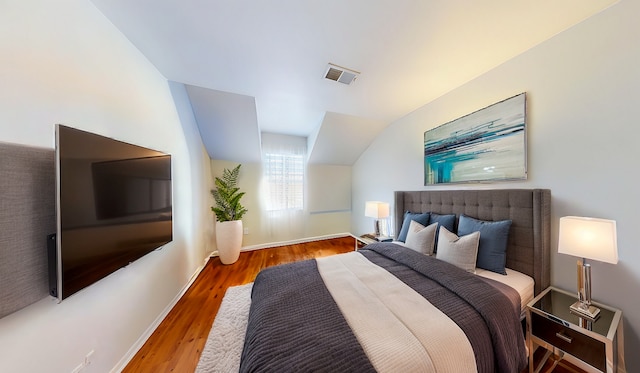 bedroom featuring visible vents, vaulted ceiling, baseboards, and wood finished floors