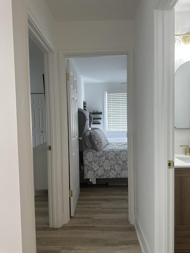 hall with a sink, baseboards, and wood finished floors