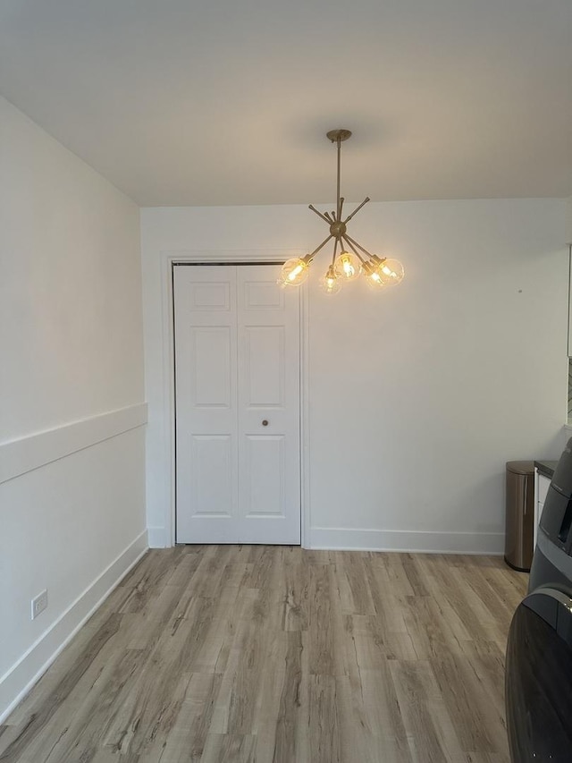 unfurnished dining area with light wood-style floors, baseboards, and a chandelier