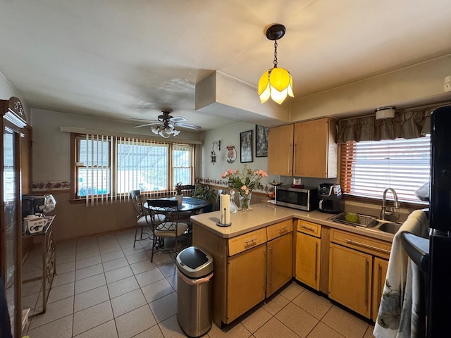 kitchen with decorative light fixtures, light countertops, stainless steel microwave, light tile patterned flooring, and a sink