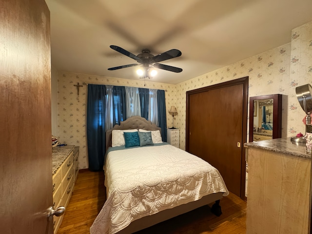 bedroom featuring wallpapered walls, a closet, dark wood-style floors, and a ceiling fan