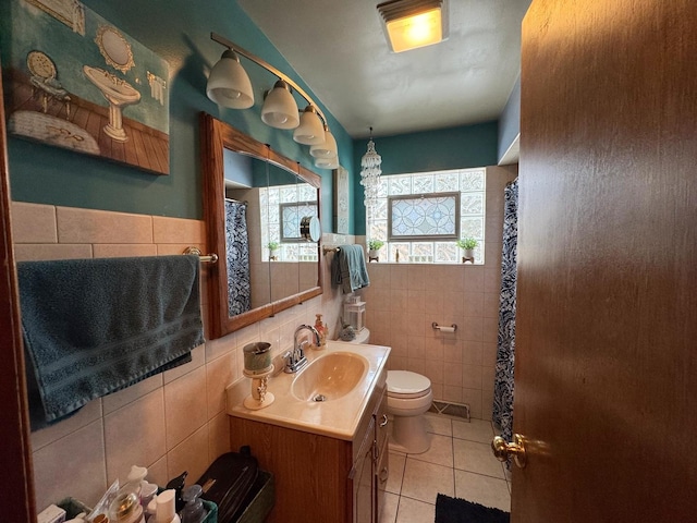 bathroom with toilet, tile patterned flooring, visible vents, and tile walls