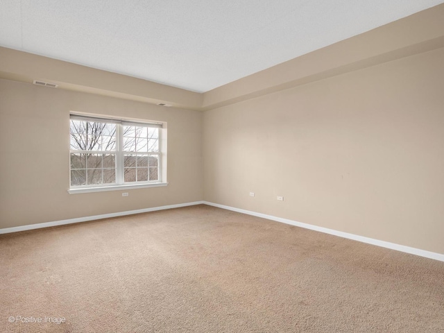 spare room with carpet floors, visible vents, and baseboards