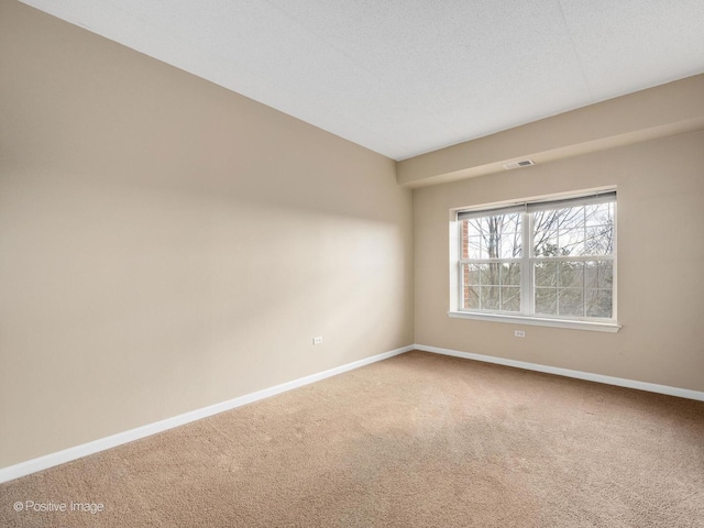 unfurnished room with carpet, visible vents, a textured ceiling, and baseboards