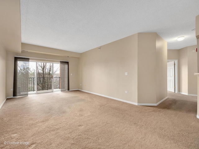 carpeted empty room with a textured ceiling and baseboards