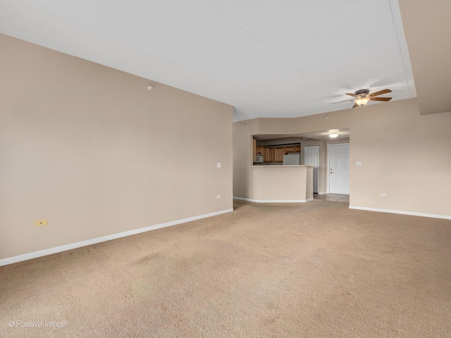 unfurnished living room with a ceiling fan, light carpet, and baseboards