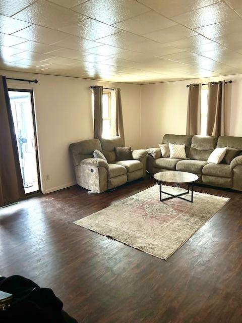 unfurnished living room featuring dark wood-type flooring and baseboards