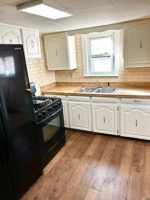 kitchen featuring black appliances, a sink, light countertops, and white cabinets