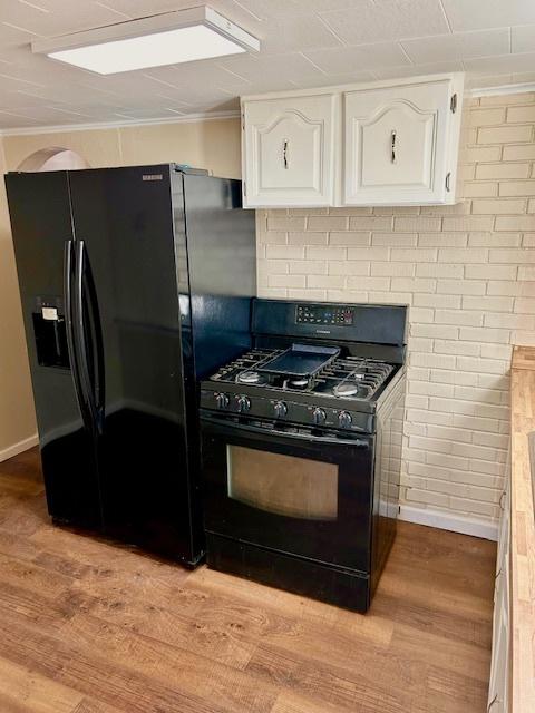 kitchen featuring black appliances, light wood finished floors, white cabinetry, and crown molding