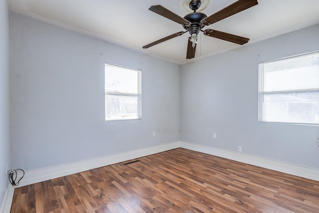 unfurnished room featuring a ceiling fan, visible vents, baseboards, and wood finished floors