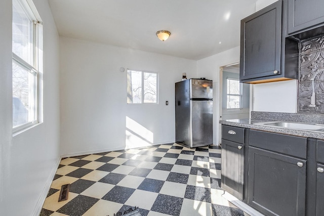 kitchen featuring freestanding refrigerator, plenty of natural light, dark countertops, and dark floors