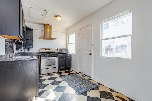 kitchen featuring dark countertops, wall chimney exhaust hood, stainless steel range with gas cooktop, and dark floors