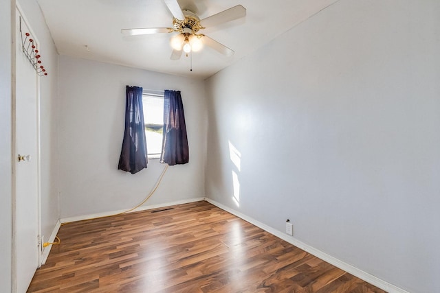 empty room featuring dark wood-type flooring, baseboards, and a ceiling fan