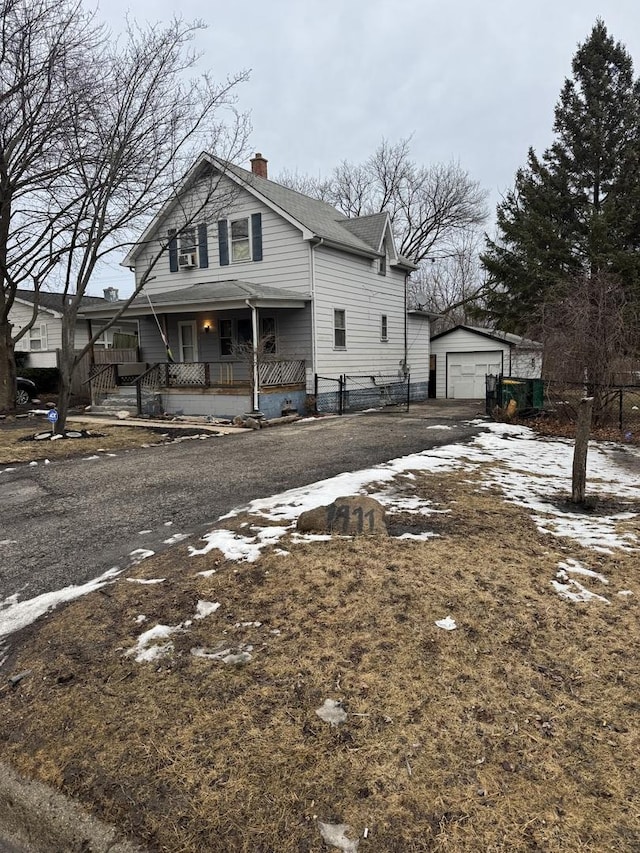 view of front of home featuring a garage, a chimney, a porch, and an outbuilding