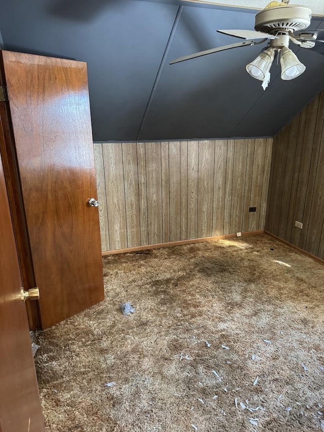 bonus room featuring lofted ceiling, wood walls, and ceiling fan