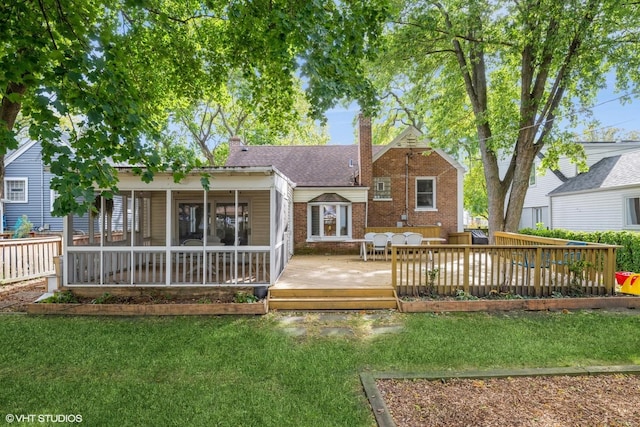 back of property with a yard, brick siding, a chimney, and a wooden deck