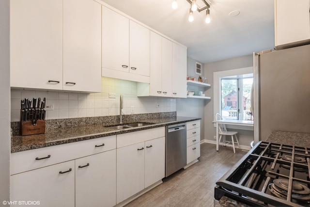 kitchen featuring freestanding refrigerator, stainless steel dishwasher, white cabinetry, open shelves, and a sink