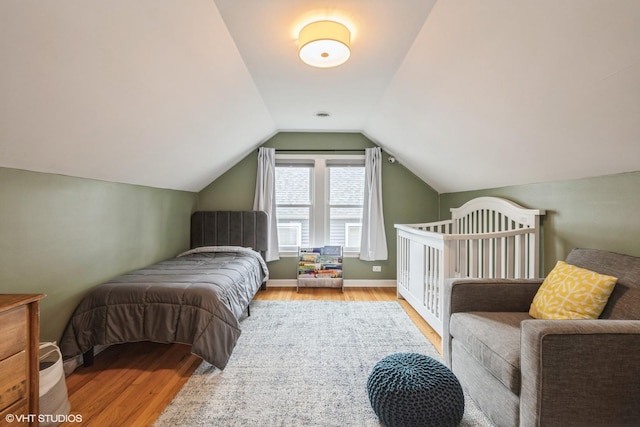 bedroom with light wood-style floors, baseboards, and vaulted ceiling