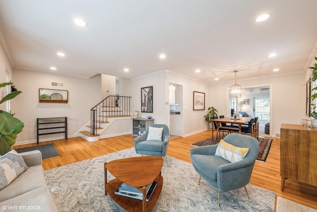 living room featuring ornamental molding, light wood-type flooring, stairway, and recessed lighting