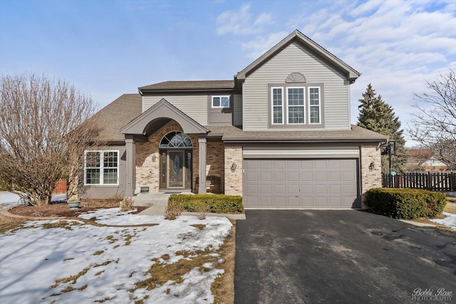 traditional-style home featuring driveway, brick siding, an attached garage, and a shingled roof