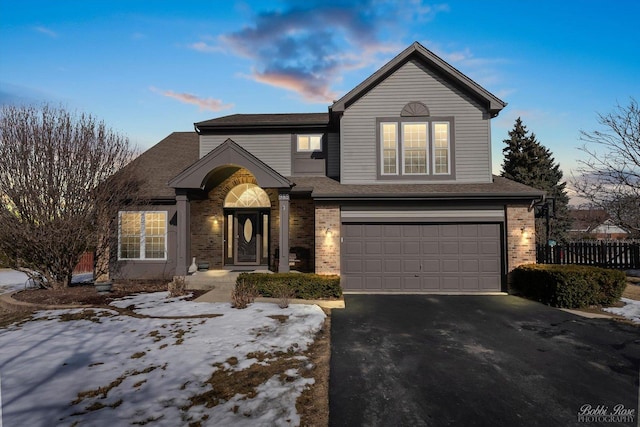 traditional-style home with a garage, driveway, brick siding, and a shingled roof