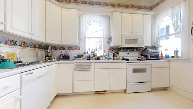 kitchen with white appliances, a sink, white cabinets, light countertops, and light floors