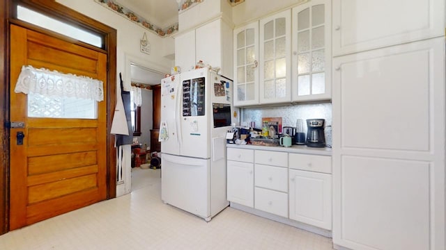 kitchen with glass insert cabinets, freestanding refrigerator, light countertops, light floors, and white cabinetry