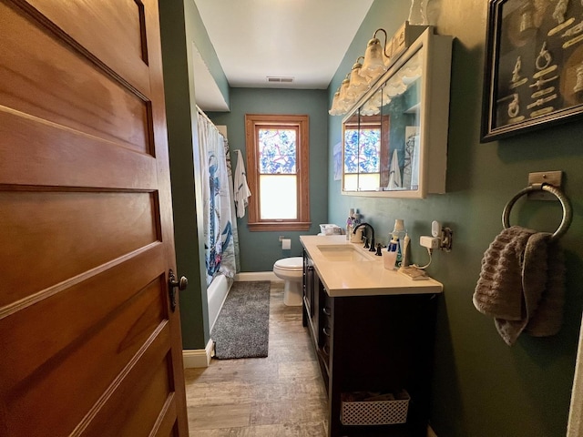 full bath featuring toilet, vanity, visible vents, baseboards, and shower / bath combo with shower curtain