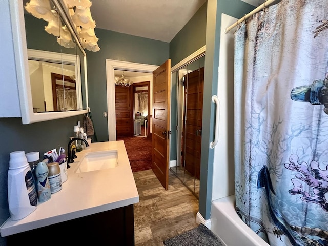 full bathroom with shower / bath combination with curtain, vanity, a notable chandelier, and wood finished floors