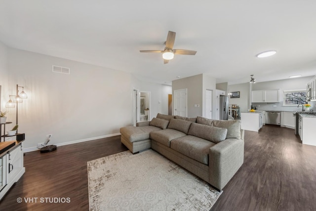 living room featuring visible vents, dark wood finished floors, baseboards, and ceiling fan