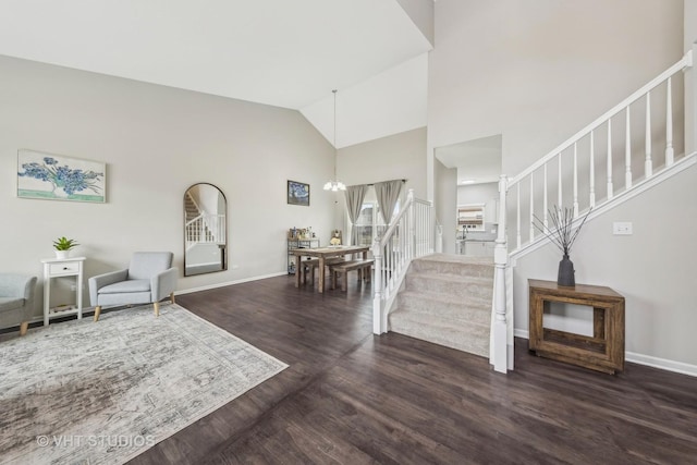 entryway featuring high vaulted ceiling, a notable chandelier, baseboards, stairs, and dark wood finished floors