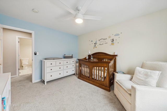 bedroom featuring light carpet, baseboards, a crib, and ceiling fan