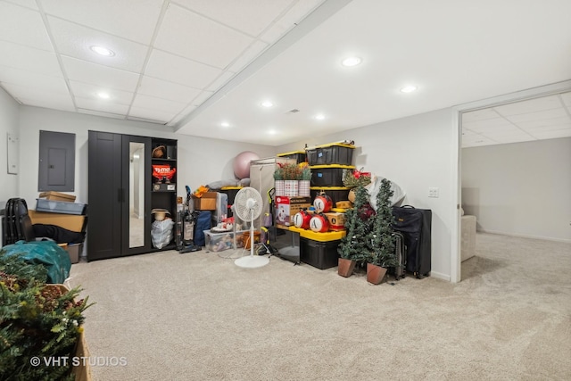 finished below grade area featuring a paneled ceiling, recessed lighting, electric panel, and light colored carpet