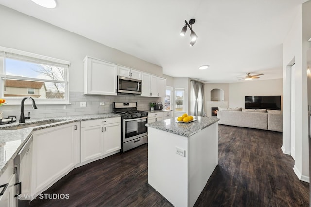 kitchen featuring light stone counters, appliances with stainless steel finishes, white cabinets, and a sink